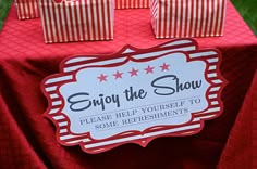 red and white table cloth with small bags on it that says, enjoy the show please help yourself to some refreshments