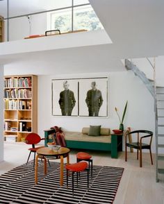 a living room filled with lots of furniture and bookshelves next to a stair case