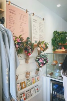 a woman standing in front of a display case filled with flowers and cards on the wall