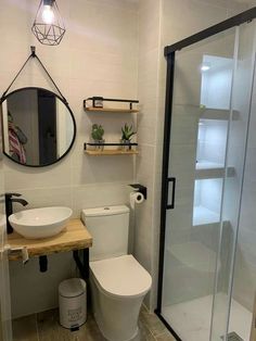 a white toilet sitting next to a walk in shower under a bathroom mirror above a sink