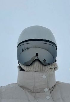 a person wearing ski goggles and a white jacket is standing in front of the sky