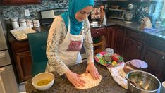 a woman in an apron is kneading some food