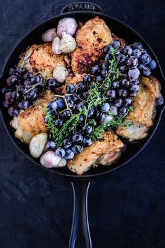 a skillet filled with chicken, potatoes and blueberries