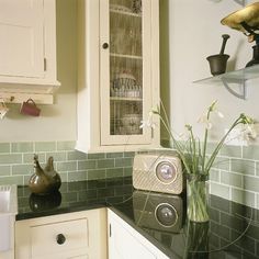 a kitchen with white cabinets and green tile backsplash, including an old fashioned dishwasher