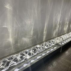 a long metal shelf with several glass bowls on it's sides in front of a white wall