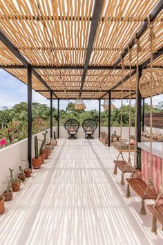 an outdoor covered patio with potted plants and benches