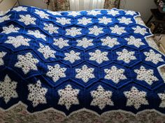 a blue and white crocheted afghan on a bed