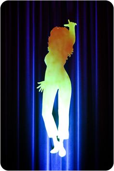 the silhouette of a woman is projected on a curtain