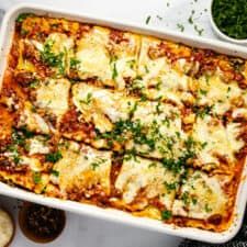 a casserole dish with meat, cheese and sauces on the side next to bread