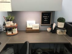 an office cubicle with desk, computer and other items on the counter top in front of a chalkboard