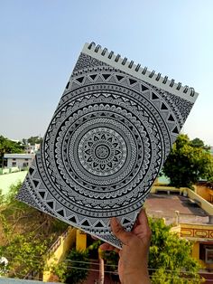 a hand holding up a spiral notebook with an intricate design