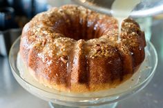 a bundt cake sitting on top of a glass cake platter next to a bottle of wine