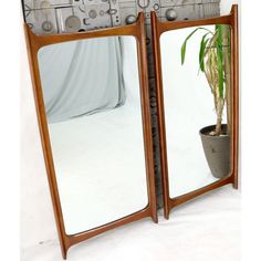 two wooden mirrors sitting next to each other on a white surface with a potted plant in it