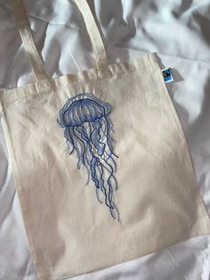 a white bag with a blue jellyfish embroidered on it