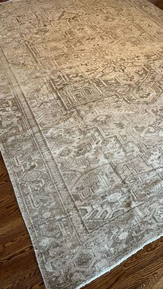 an old rug is laying on the floor in front of a wooden flooring area