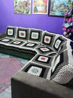 a crocheted couch in front of purple walls with pictures on the wall behind it