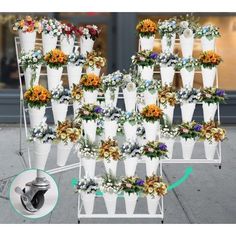 a bunch of white vases filled with flowers on top of a metal rack next to a sidewalk