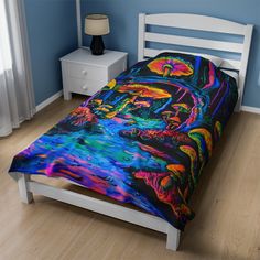 a bed with a colorful comforter on it in a room next to a night stand