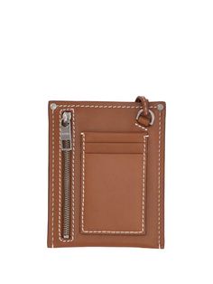 Expertly crafted from soft calf leather, the Jacquemus Le Porte Poche Meunier Logo Plaque Wallet is a versatile piece to carry your essentials in style. Its compact dimensions make it perfectly portable for on-the-go days yet fits credit cards, cash, and receipts with room to spare. Detailed with the signature Jacquemos brass plaque and adjustable chain strap allowing wear as a crossbody, this wallet ensures your outfit is Instagram-worthy wherever the day takes you. Lasting quality and chic des Designer Leather Clutch With Card Slots, Modern Brown Wallet With Interior Key Chain Holder, Modern Brown Wallets With Removable Pouch, Modern Brown Wallet With Removable Pouch, Leather Bifold Clutch With Zipper Closure, Brown Leather Wallet On Chain With Card Slots, Leather Wallet On Chain With Card Slots, Luxury Clutch Wallet With Cell Phone Pocket, Rectangular Leather Wallet On Chain With Card Slots