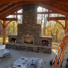 an outdoor fireplace is being built in the middle of a patio with ladders on it