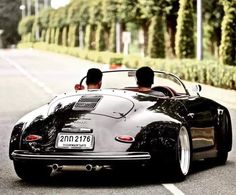 two people in a black sports car driving down the road