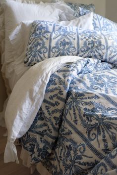 an unmade bed with blue and white comforter