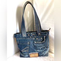 a denim purse with studded details on the front and sides, sitting against a white background