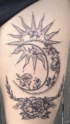 a woman's thigh with an image of the sun and moon on it, surrounded by flowers