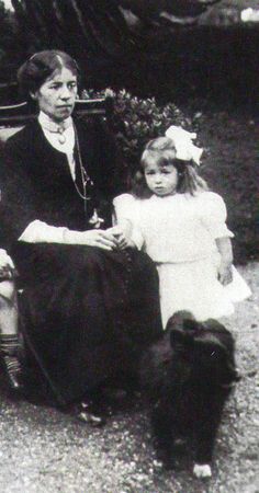 an old black and white photo of two people sitting on a bench with a dog