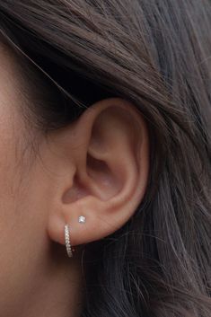 a close up view of a woman's ear with two diamond earrings on it