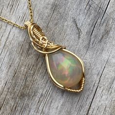 This gorgeous Ethiopian Opal pendant is hand wrapped using elegant 14k yellow gold filled wire. With a gray base, it has a stunning play of color consisting of orange, red, green, yellow, pink, and some light blue and purple in certain lighting. The opal weighs 7.35 carats before wrapped. This pendant measures about 1.5 inches tall from the bottom of pendant to the top of the bail. A complimentary 14k gold filled chain is included! Chain is removable and interchangeable. I did my best to provide Unique 14k Gold Wire Wrapped Jewelry, Hand Wrapped Yellow Gold Jewelry As Gift, Hand-wrapped Yellow Gold Jewelry Gift, Hand Wrapped Yellow Gold Jewelry Gift, Hand Wrapped Spiritual Jewelry For Anniversary, Spiritual Hand Wrapped Jewelry For Anniversary, Handmade Ethiopian Opal Jewelry For Anniversary, Elegant Hand Wrapped Pendant Jewelry, Gold Opal Wedding Jewelry