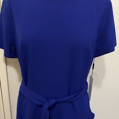 This Calvin Klein Royal Blue Dress Is Made Of A Stretch Crpe Fabric. It Has A Around Neck, Short Sleeves, Belt Waist, Ruffle On The Skirt, And A Gold Back Zipper. How The Waist Is 34, The Bust Is 43, The Hip Is 45, And The Length Is 41. It’s New With Tags. It Has No Stains Or Rips. Blue Short Sleeve Belted Midi Dress, Blue Belted Midi Dress With Short Sleeves, Blue Belted Short Sleeve Dress, Blue Belted Fitted Dress, Blue Fitted Belted Dress, Blue Tie Waist Midi Dress For Formal Occasions, Blue Tie Waist Dress For Formal Occasions, Elegant Blue Belted Mini Dress, Blue Tie Waist Formal Dress