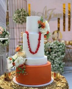 a white and orange wedding cake with flowers on top