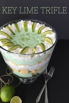 a glass bowl filled with white and green flowers on top of a black table next to utensils