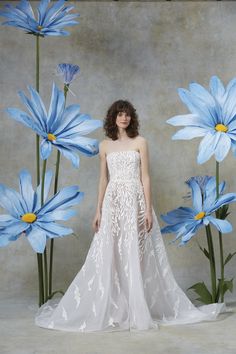 a woman standing in front of blue flowers