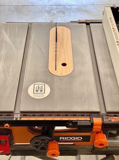 a table saw is sitting on top of a piece of metal with an orange handle