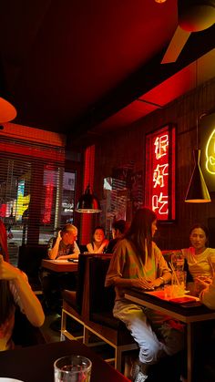 people sitting at tables in a restaurant with neon signs