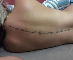 a woman laying on top of a bed with her back turned to the camera and tattoo