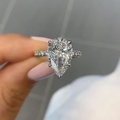 a woman's hand holding an engagement ring with two pear shaped diamonds