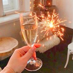 a person holding a wine glass with sparklers in it