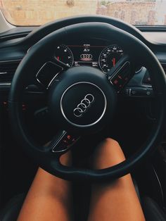 a person sitting in the driver's seat of a car with their feet on the steering wheel