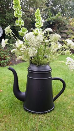 a black watering can with flowers in it