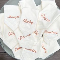 embroidered napkins with names on them sitting in a bowl