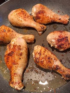 four pieces of chicken cooking in a frying pan