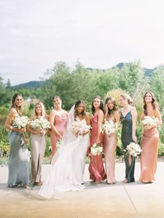 a group of women standing next to each other holding bouquets in their hands and smiling at the camera