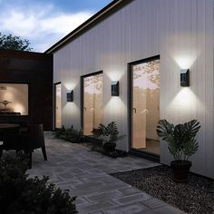 an exterior view of a house with several lights on the side and plants in front