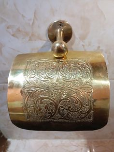 a gold colored toilet paper holder hanging from the wall