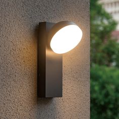 a close up of a light on the side of a building with trees in the background