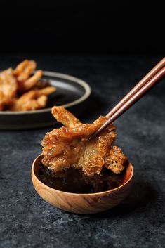 a wooden bowl filled with fried food and chopsticks