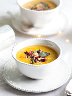 two white bowls filled with soup on top of a table